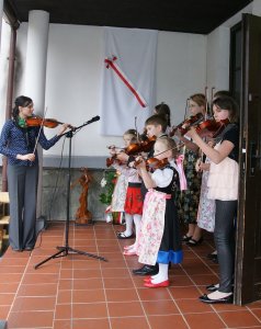 Uczniowie Ogniska w strojach regionalnych grają przed budynkiem willi "Beskid"